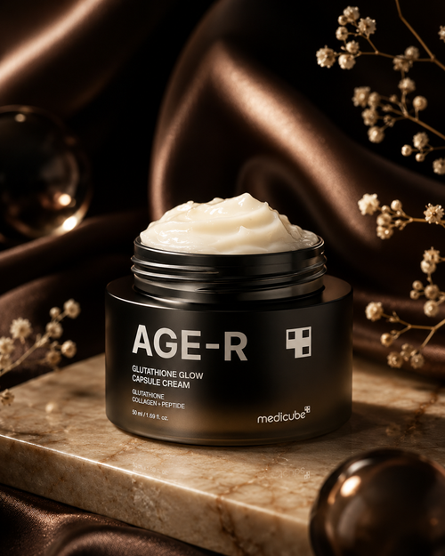 medicube AGE-R Glutathione Glow Capsule Cream 50ml open jar with rich white cream texture, displayed on marble surface with silk fabric and dried flowers in warm brown tones