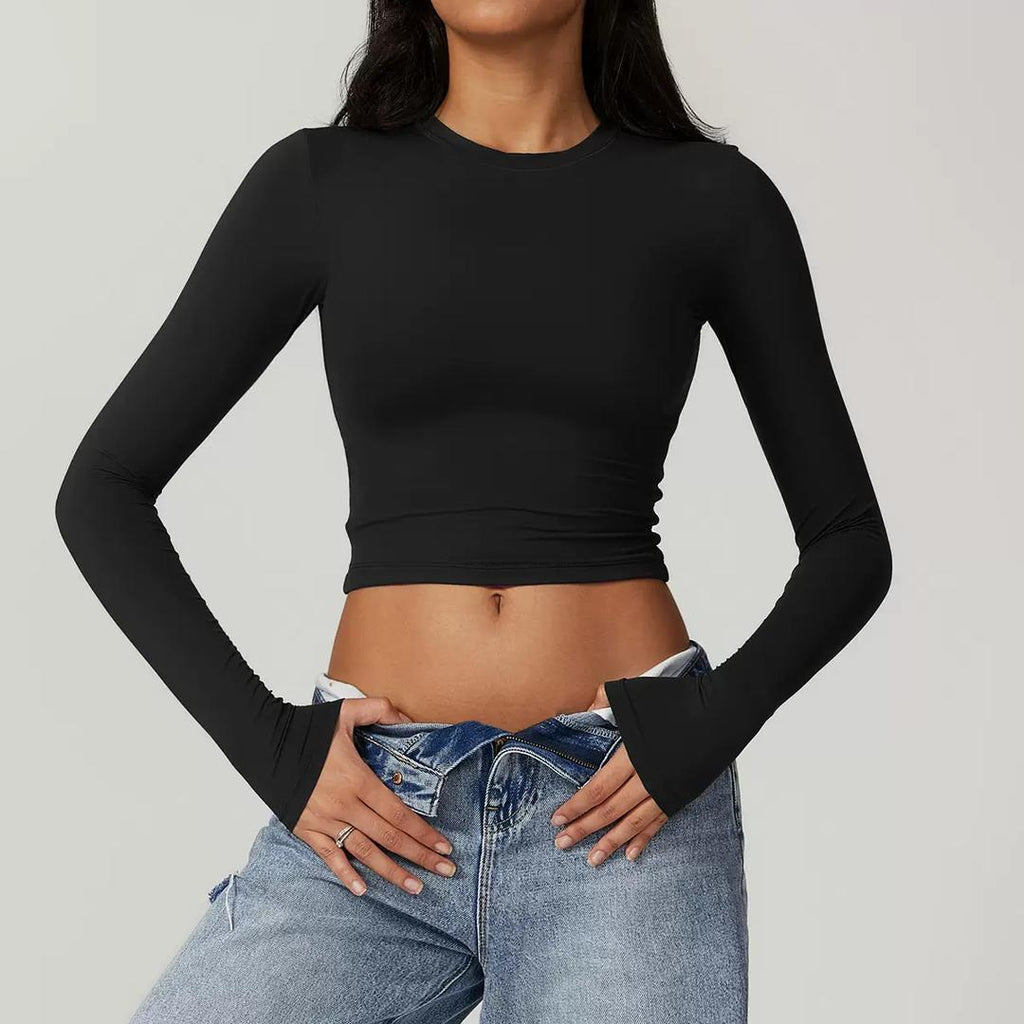 Person wearing a black long-sleeve crop top and blue jeans on a gray background