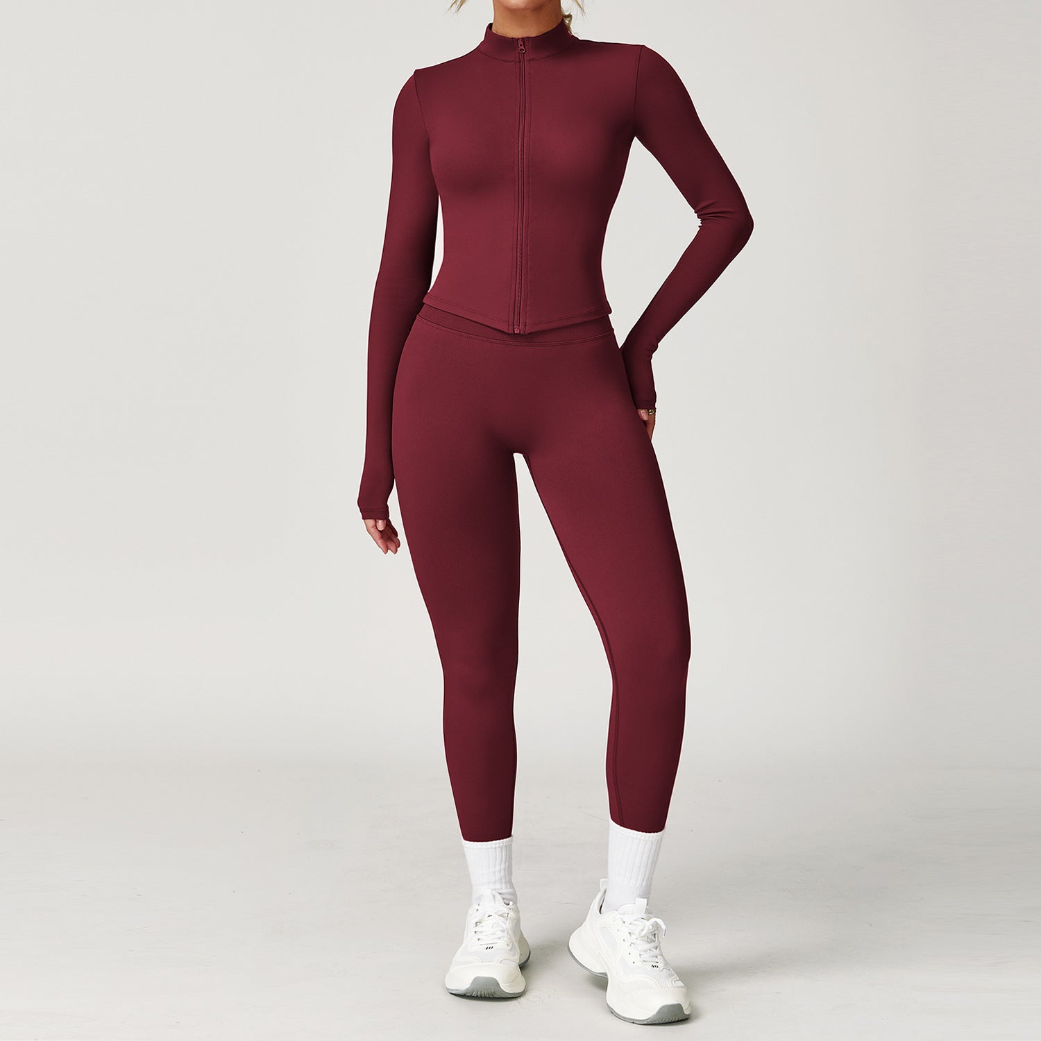 Maroon athletic outfit with long-sleeve top and leggings on a plain background