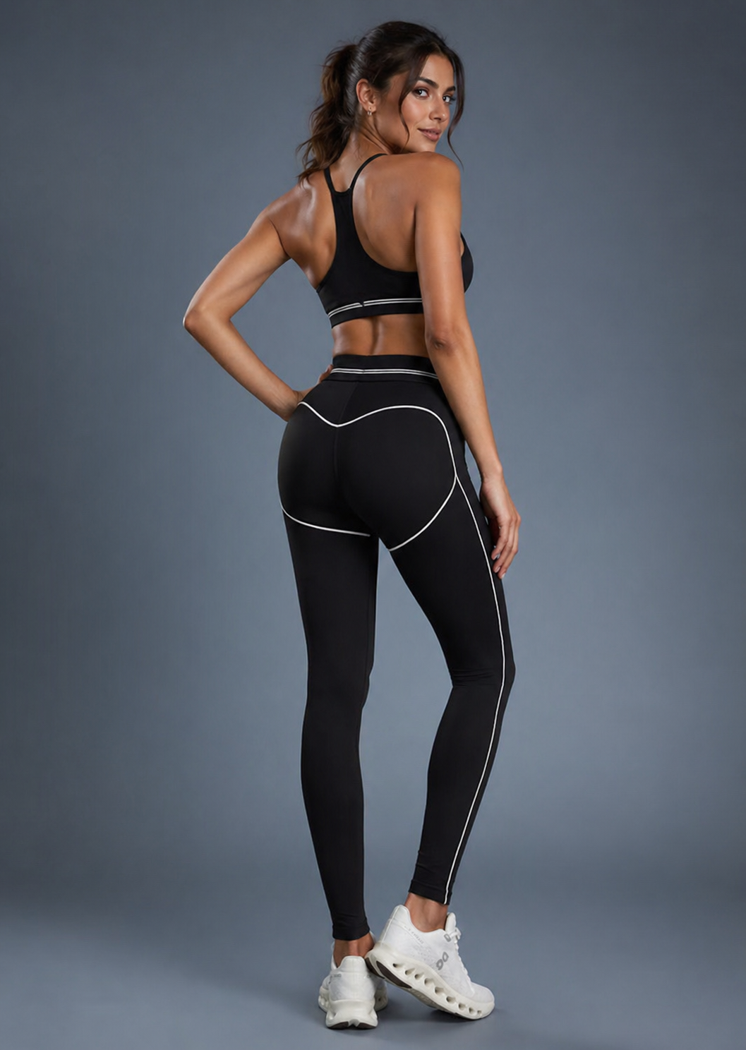 Woman wearing a black athletic outfit with white accents on a gray background
