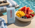 Tocobo sunscreen stick next to a bowl of fruit by a poolside.