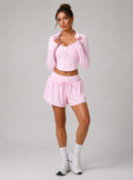 Woman wearing a pink athletic outfit on a plain background